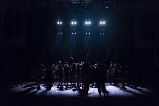 Audience silhouetted against a brightly lit stage