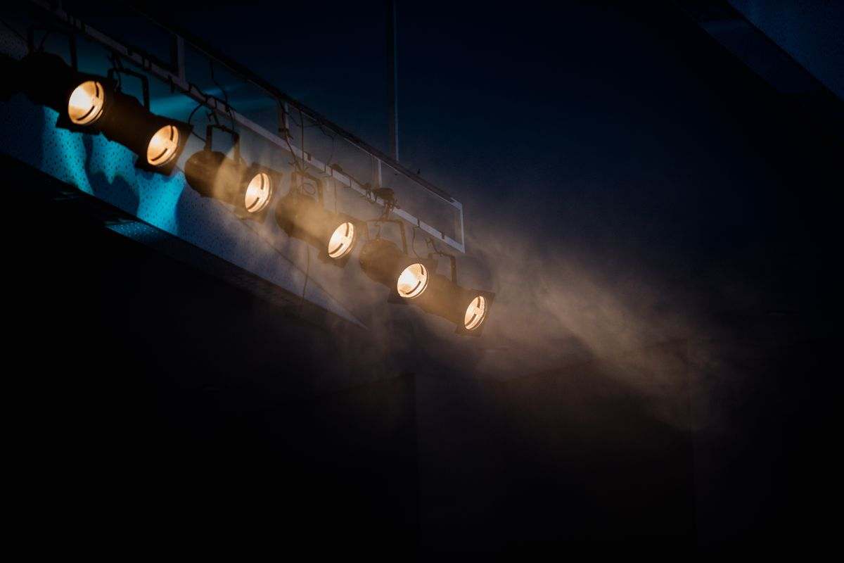 Stage lights cutting through haze above an audience